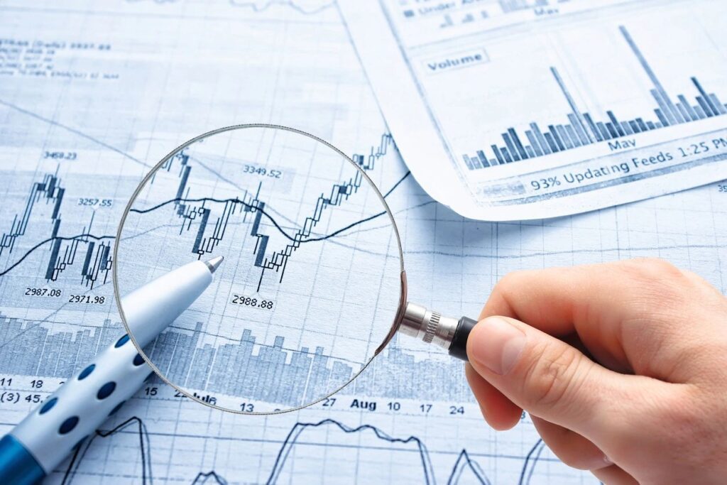 Businessman holding magnifying glass with chart papers